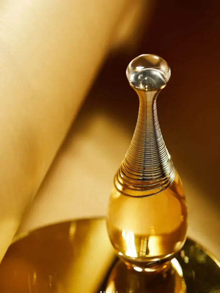 Dior J'adore Infinissime perfume bottle on a gold background, showcasing luxurious floral fragrance.