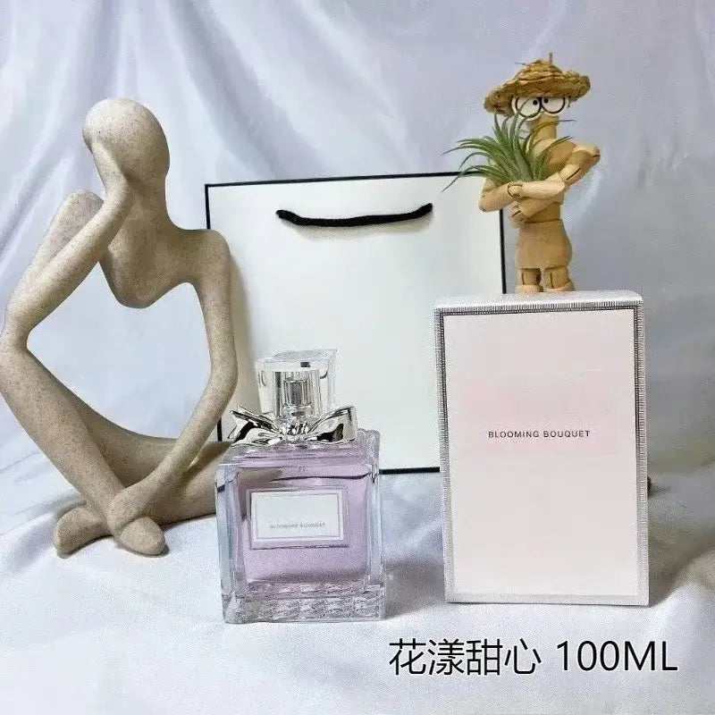 Women's Floral Body Spray 100ml - Long-Lasting Romantic Perfume displayed with packaging and decorative figurines.
