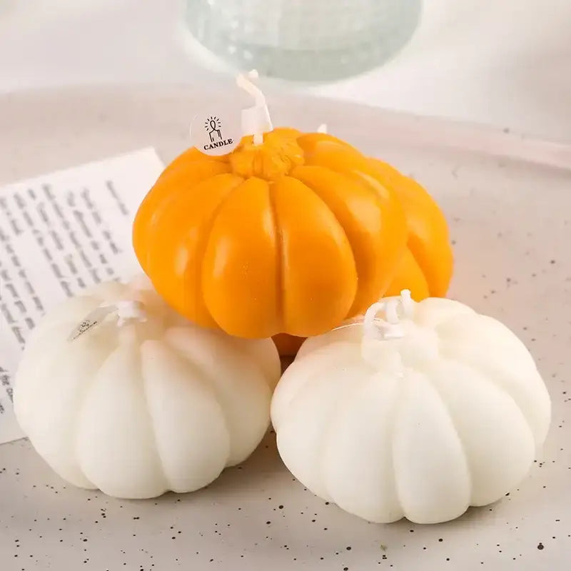 Pumpkin-shaped candle in orange and white, made of wax with a wooden wick.